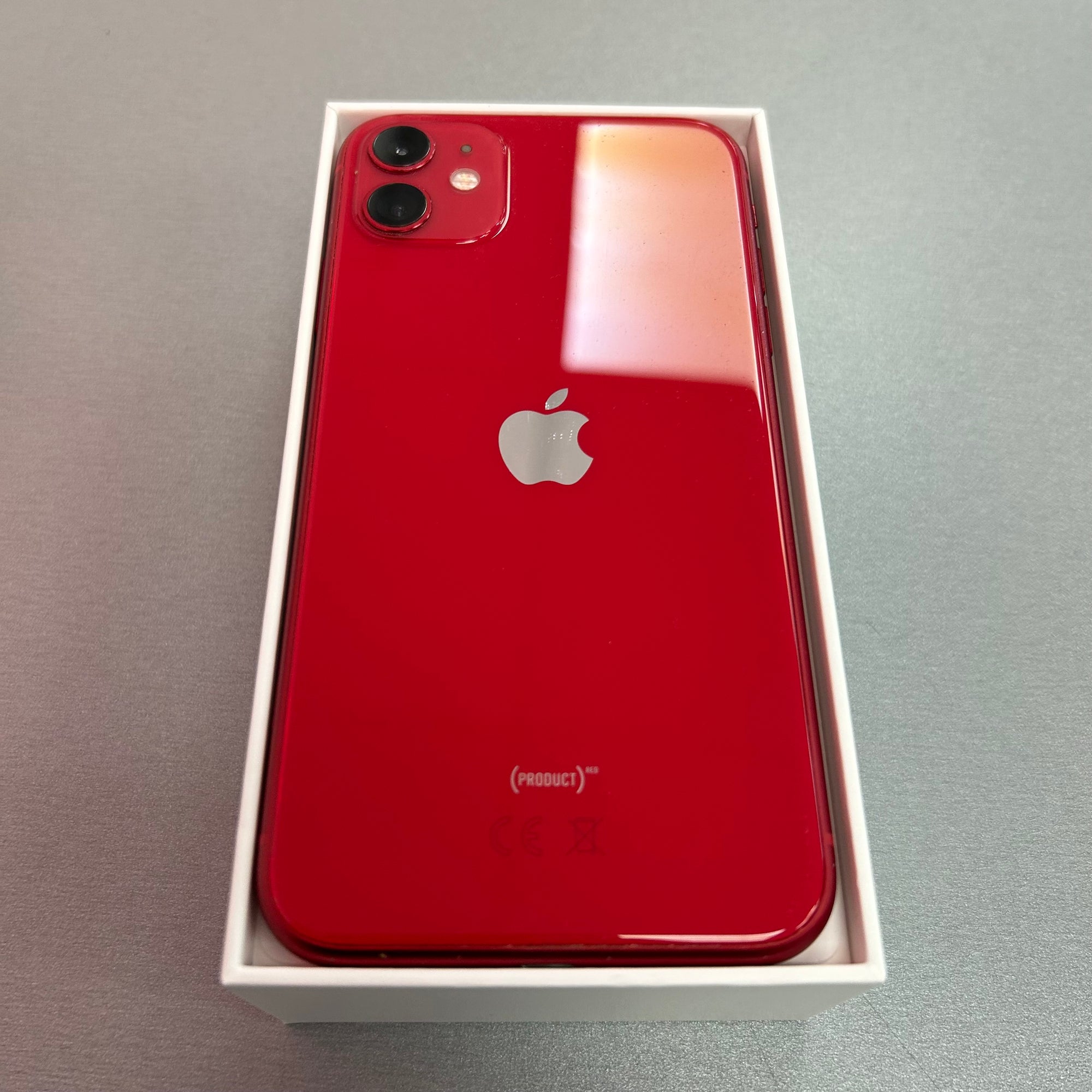 Red smartphone with Apple logo in a box on a gray background