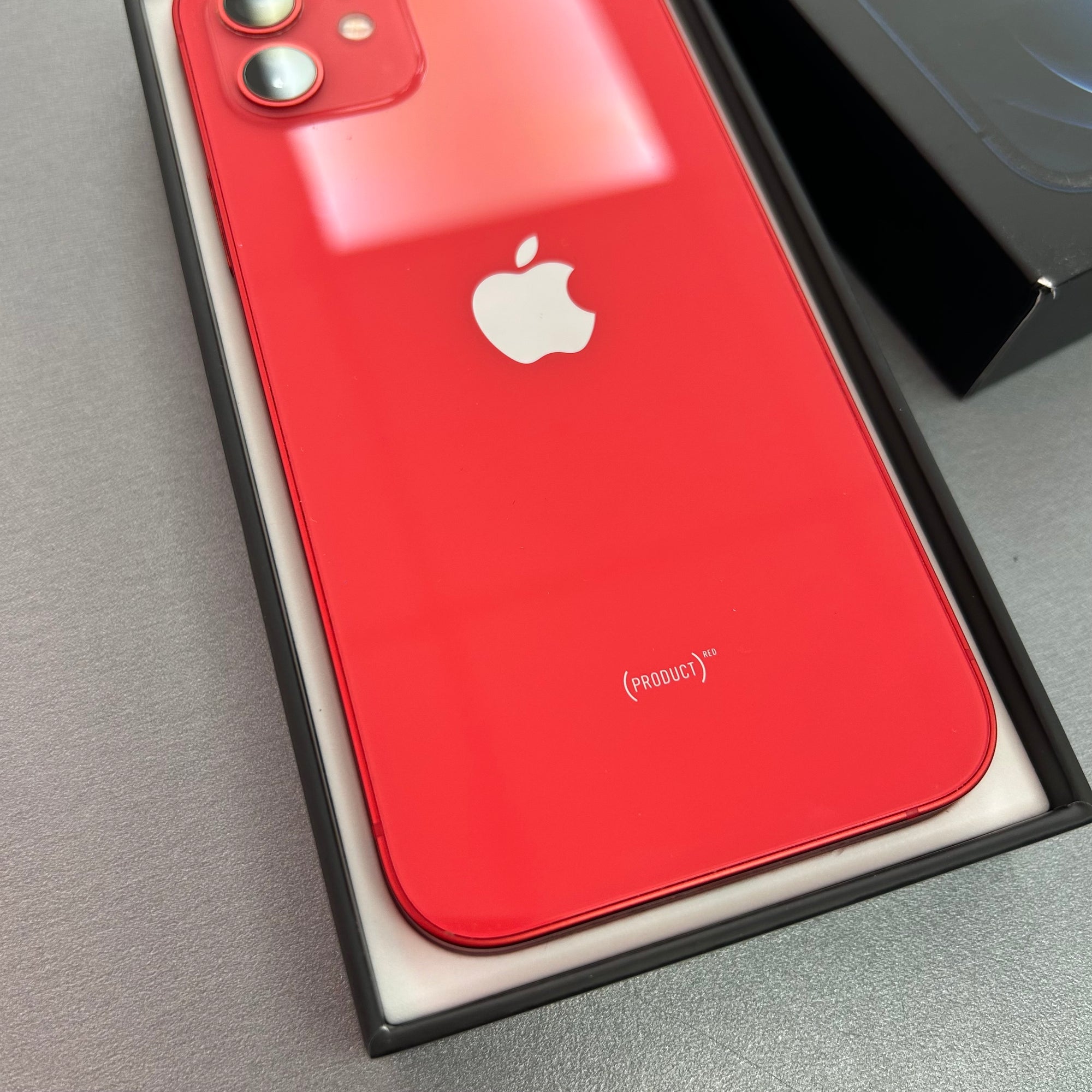 Red smartphone with Apple logo in a box on a gray surface