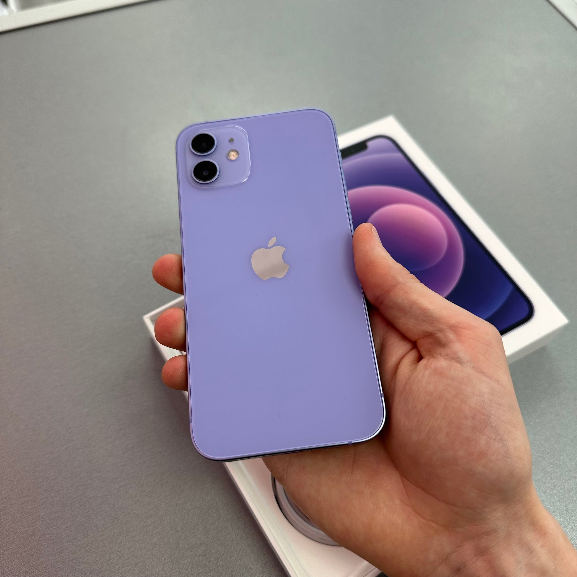 Purple iPhone 11  held in a hand with a gray background AT TIME2TALK SWANSEA 