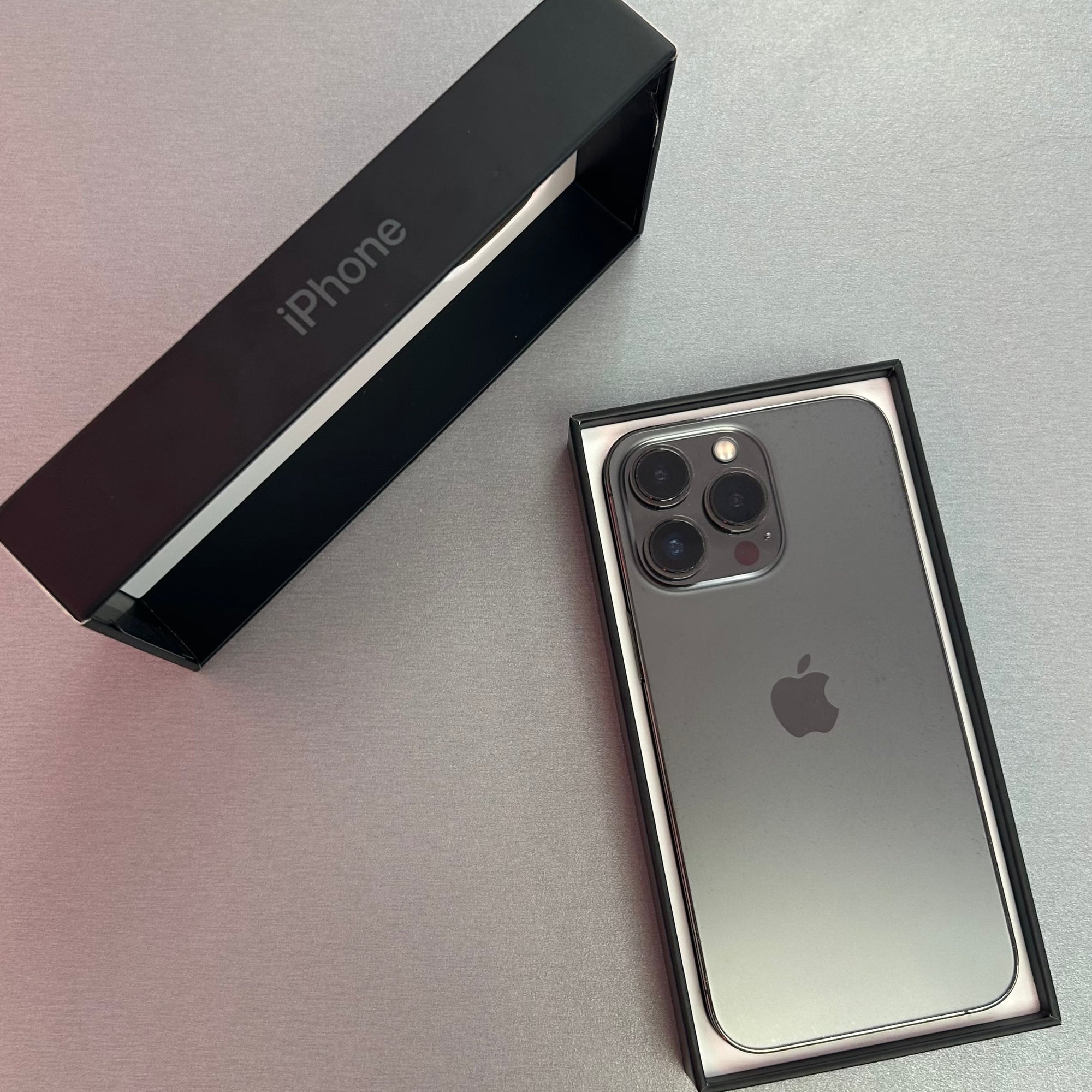 Silver iPhone 13 Pro with Apple logo on a reflective surface