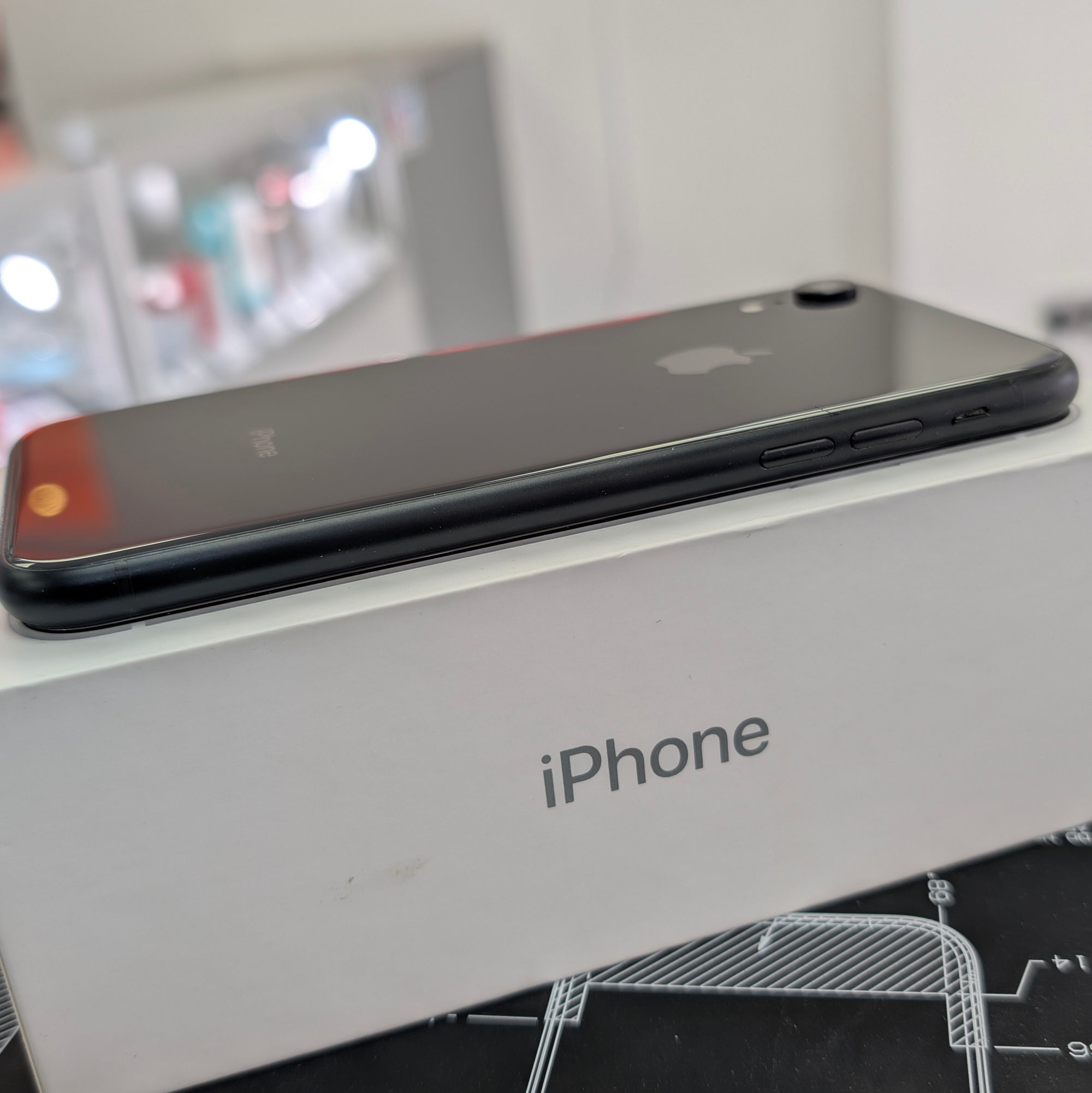 Black iPhone on top of an iPhone box with a blurred background