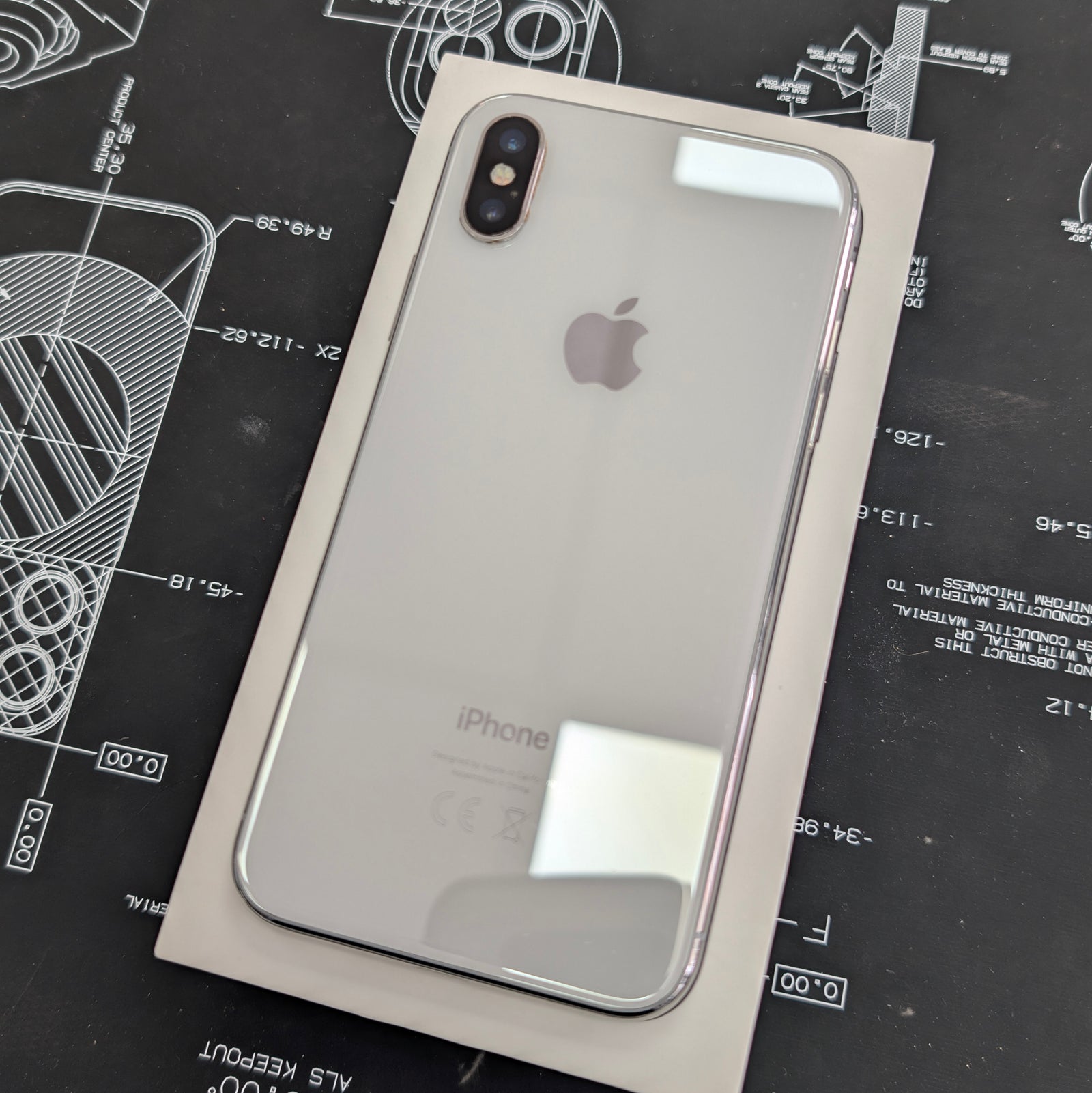 Back view of an iPhone X on a black technical drawing background