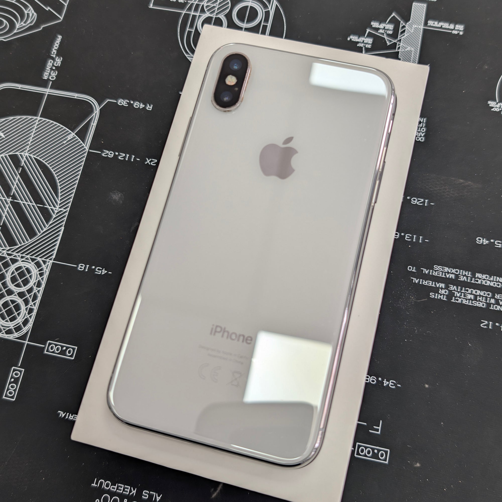Back view of an iPhone X on a black technical drawing background