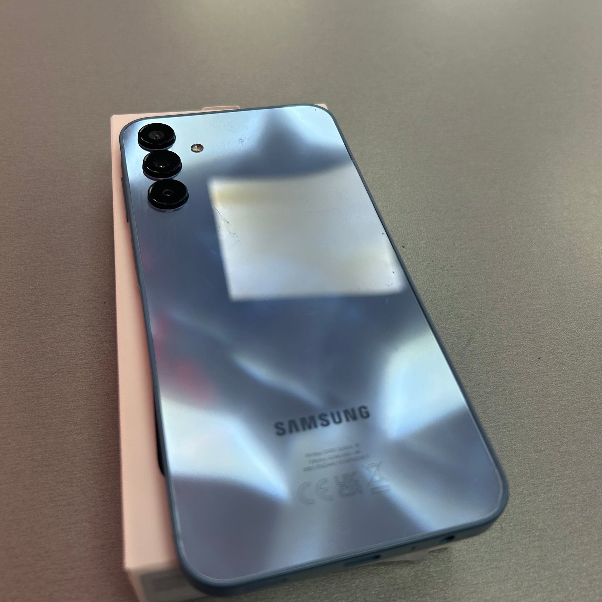 Samsung smartphone with reflective back on a gray surface