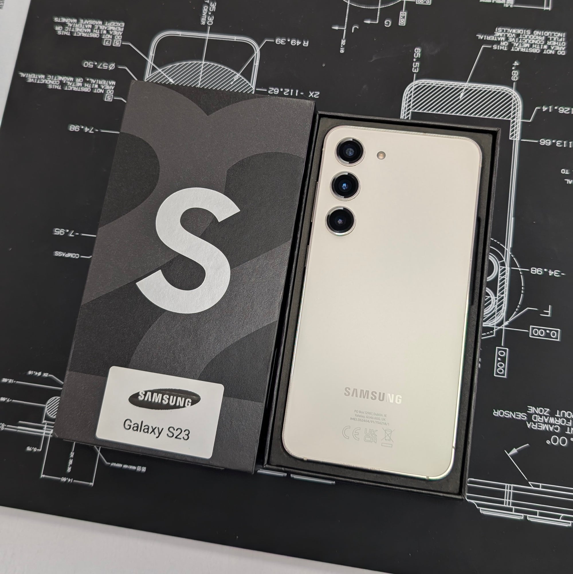 Samsung Galaxy S23 phone in packaging on a technical drawing background